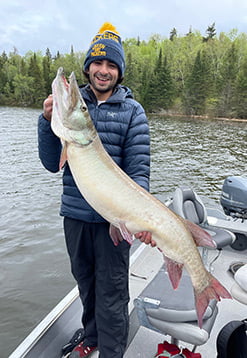 young man holding up massive muskie caught fishing